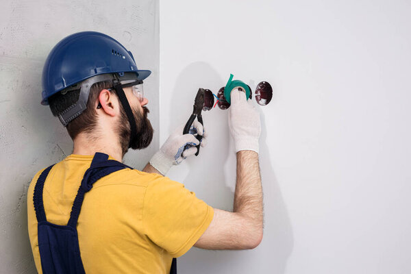 electrician in helmet installs sockets