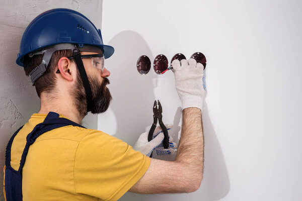 electrician in helmet installs sockets