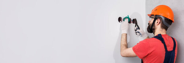 electrician in helmet installs sockets