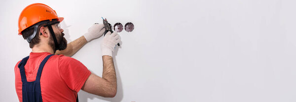 electrician in helmet installs sockets