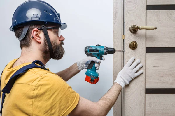Seorang Pekerja Dengan Bor Helm Oranye Memasang Pintu Rumah — Stok Foto