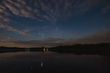 Ormanın yanındaki göl yıldızlı yaz gökyüzünün altında ay ışığında