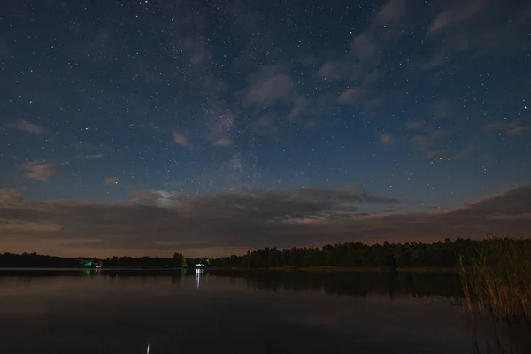 月明かりの下で星空の下で森に囲まれた湖 — ストック写真