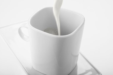 Chorro de leche sobre taza blanca