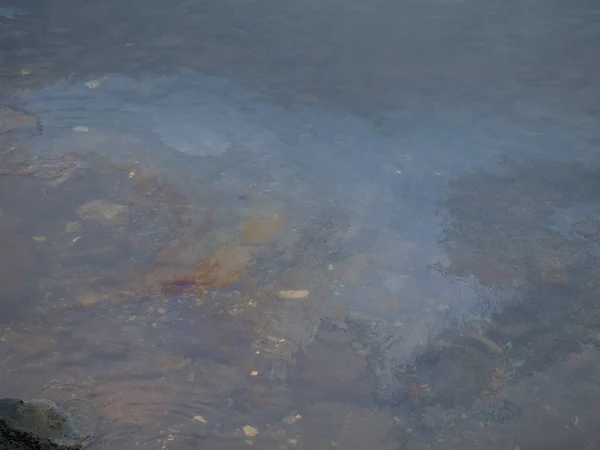 ビーチでターコイズブルーの海の表面に汚れた油性フィルム 産業廃棄物の水の流出油膜汚染 水の上のカラフルな油膜 産業廃棄物処理水の流出 虹の海 — ストック写真