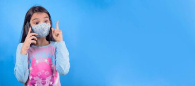 young woman with face mask and blue eyes on color background