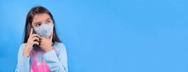 Siyah maskeli komik bir kız. Coronavirus mavisi. Komik bir ifade. Covid-19. Panorama arka planı. Kes şunu-19.