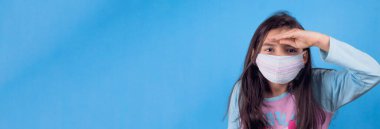 Siyah maskeli komik bir kız. Coronavirus mavisi. Komik bir ifade. Covid-19. Panorama arka planı. Kes şunu-19.