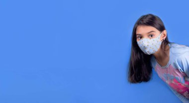 Siyah maskeli komik bir kız. Coronavirus mavisi. Komik bir ifade. Covid-19. Panorama arka planı. Kes şunu-19.