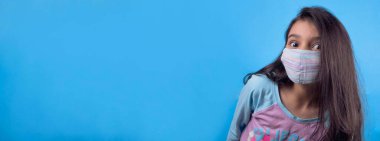 Siyah maskeli komik bir kız. Coronavirus mavisi. Komik bir ifade. Covid-19. Panorama arka planı. Kes şunu-19.