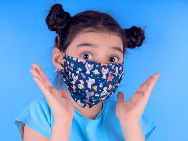 Siyah maskeli komik bir kız. Coronavirus mavisi. Komik bir ifade. Covid-19. Panorama arka planı. Kes şunu-19.