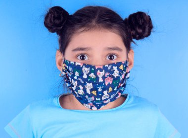 Siyah maskeli komik bir kız. Coronavirus mavisi. Komik bir ifade. Covid-19. Panorama arka planı. Kes şunu-19.