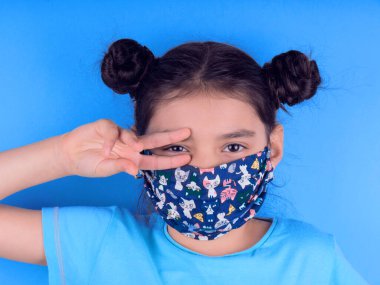 Siyah maskeli komik bir kız. Coronavirus mavisi. Komik bir ifade. Covid-19. Panorama arka planı. Kes şunu-19.
