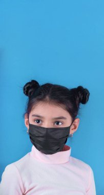 young woman in a medical mask and a blue shirt on a white background
