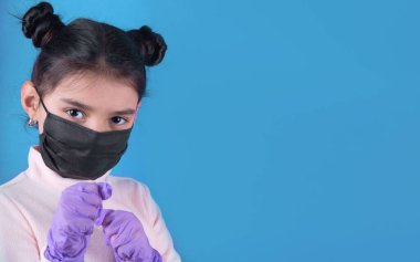 Koruyucu maske takan ve elinde virüs tutan genç bir kadın.