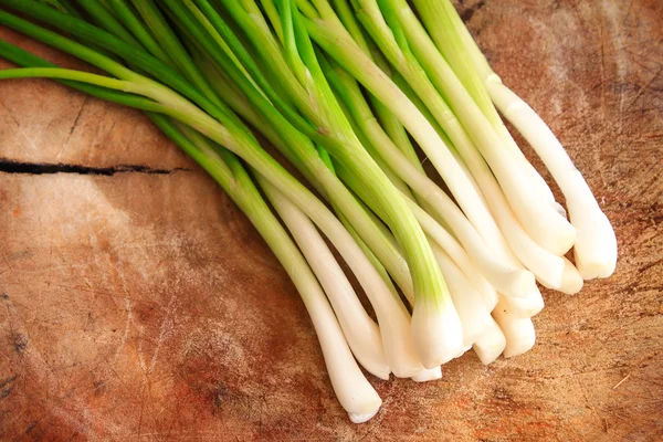 Cebollas verdes o cebolletas sobre fondo de madera — Foto de Stock