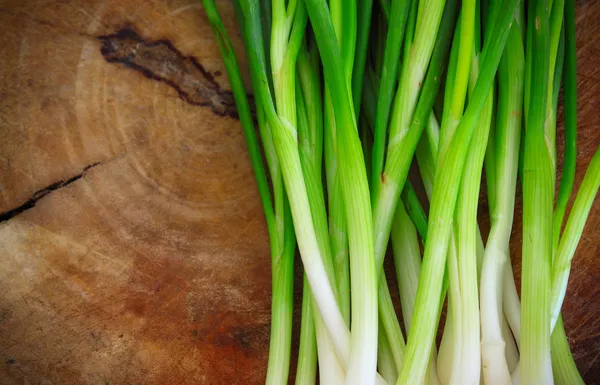 Cebollas verdes o cebolletas sobre fondo de madera — Foto de Stock