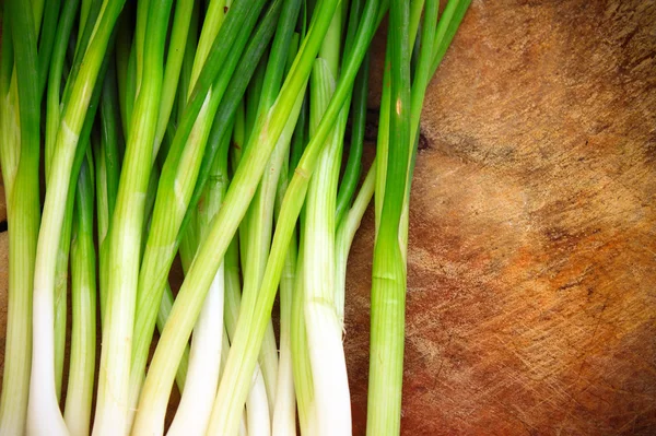 Green onions or scallions on wood background — Stock Photo, Image