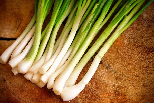 Cebollas verdes o cebolletas sobre fondo de madera Imagen De Stock