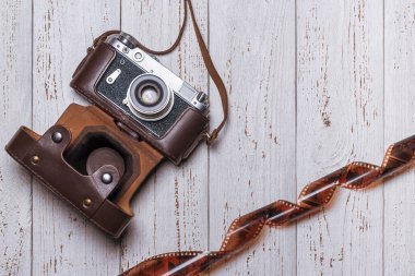 İçinde film olan kahverengi deri bir çantada eski bir retro kamera. Eski tahtalardan arkaplan