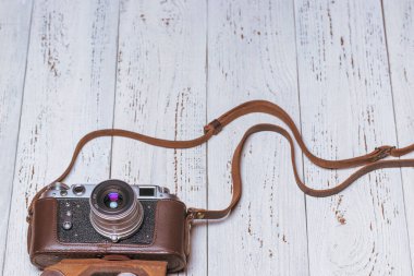 Kahverengi deri bir çantada eski bir retro kamera. Eski tahtalardan arkaplan
