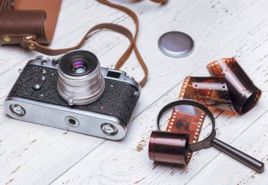 Deri çantalı eski bir retro kamera, büyüteç ve beyaz tahtalar üzerinde bir film. Vintage fotoğraf