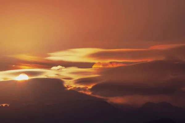 太陽は山の丘のシルエットの上の雲の間から昇る 朝のもや — ストック写真
