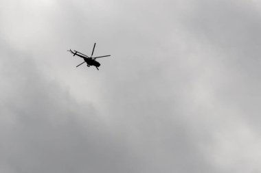 Bulutlu gökyüzünde uçan helikopter.