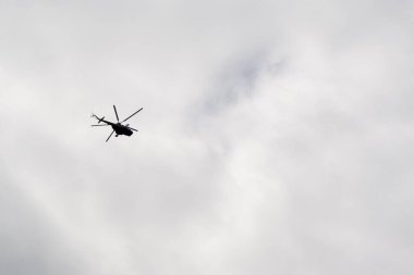 Bulutlu gökyüzünde uçan helikopter.