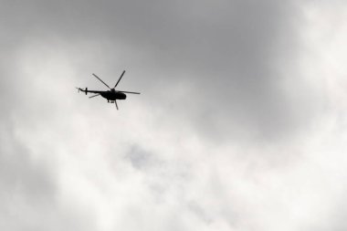 Bulutlu gökyüzünde uçan helikopter.