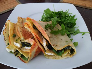 Peynirli ve tabakta sebzeli leziz krepler.