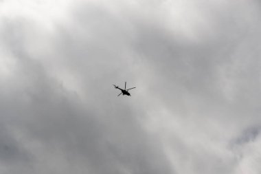 Bulutlu gökyüzünde uçan helikopter.