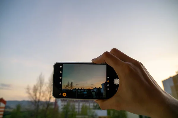 夕日の空を背景に携帯電話の写真を撮る女性 — ストック写真