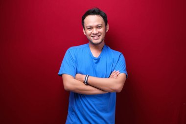 Kırmızı üzerine izole edilmiş siyah gömlek giyen gülümseyen Asyalı genç adamın portresi..