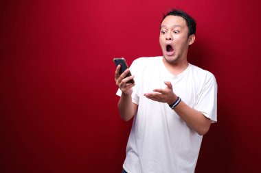 Genç Asyalı bir adam akıllı telefonu işaret ettiğinde şok olur.