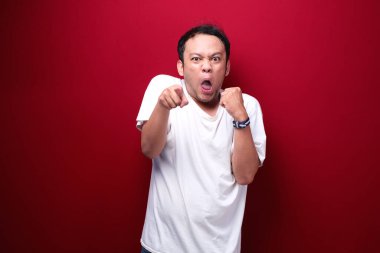 Kızgın ve stresli Asyalı genç adam kolunu kaldırıyor..