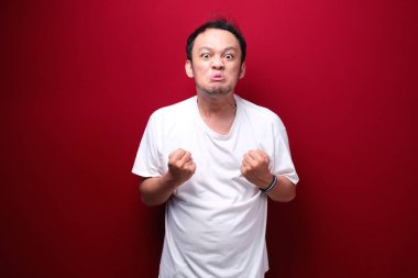 Kızgın ve stresli Asyalı genç adam kolunu kaldırıyor..