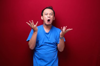 Kızgın ve stresli Asyalı genç adam kolunu kaldırıyor..