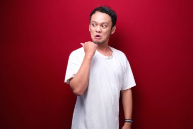 Boş alanda eli işaret eden gömlekli genç Asyalı adamın kızgın ve nefret dolu yüzü..