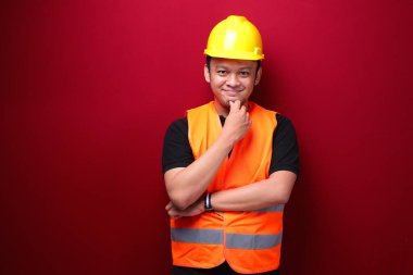 Genç Asyalı işçiyi ciddi ciddi kırmızı arka planda bir jest olarak düşünmek.