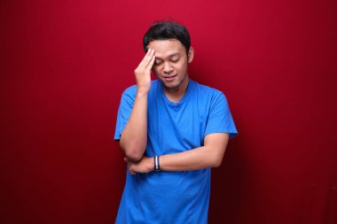 Genç Asyalı adamın kırmızı arka planda ciddi bir jest yaptığını düşünüyorum.