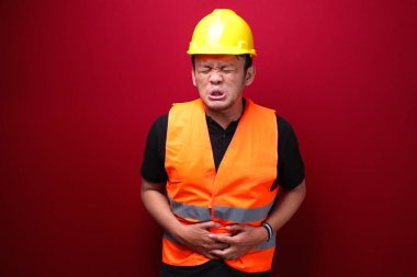 Ciddi karın ağrısı olan Asyalı genç bir işçi.