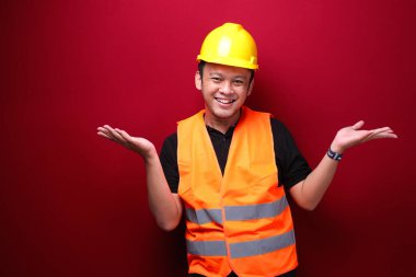 Genç Asyalı işçi mutlu ve el hareketleriyle gülümsüyor.