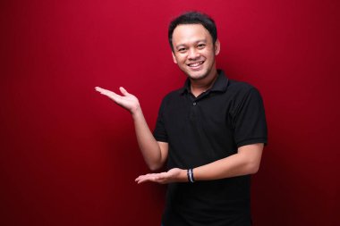 Gülümse ve mutlu Asyalı genç adam boşluğu işaret ediyor.