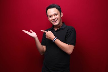 Gülümse ve mutlu Asyalı genç adam boşluğu işaret ediyor.