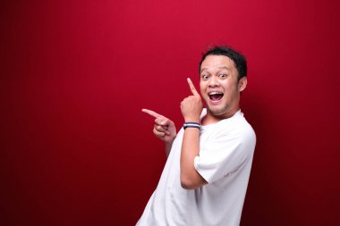 Gülümse ve mutlu Asyalı genç adam boşluğu işaret ediyor.