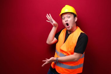 Genç Asyalı işçi şaşırmış ve haykırıyor elleri kırmızı arka planda izole bir şekilde sağa dönük..