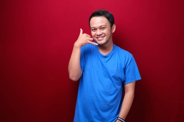 Gülümseyen Asyalı genç adam konuşuyor ya da el hareketi yapıyor.