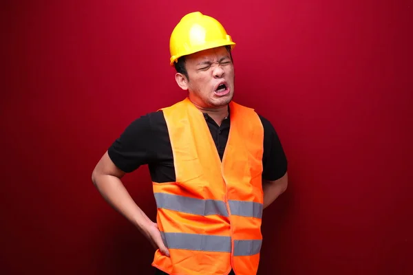 Üzgün ve üzgün Asyalı bir işçi. Sırtında ciddi bir ağrı var.