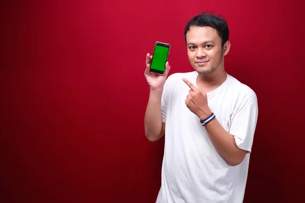 Ung Asiatisk Man Pekar Grönt Tomt Utrymme Smartphone Röd Bakgrund — Stockfoto